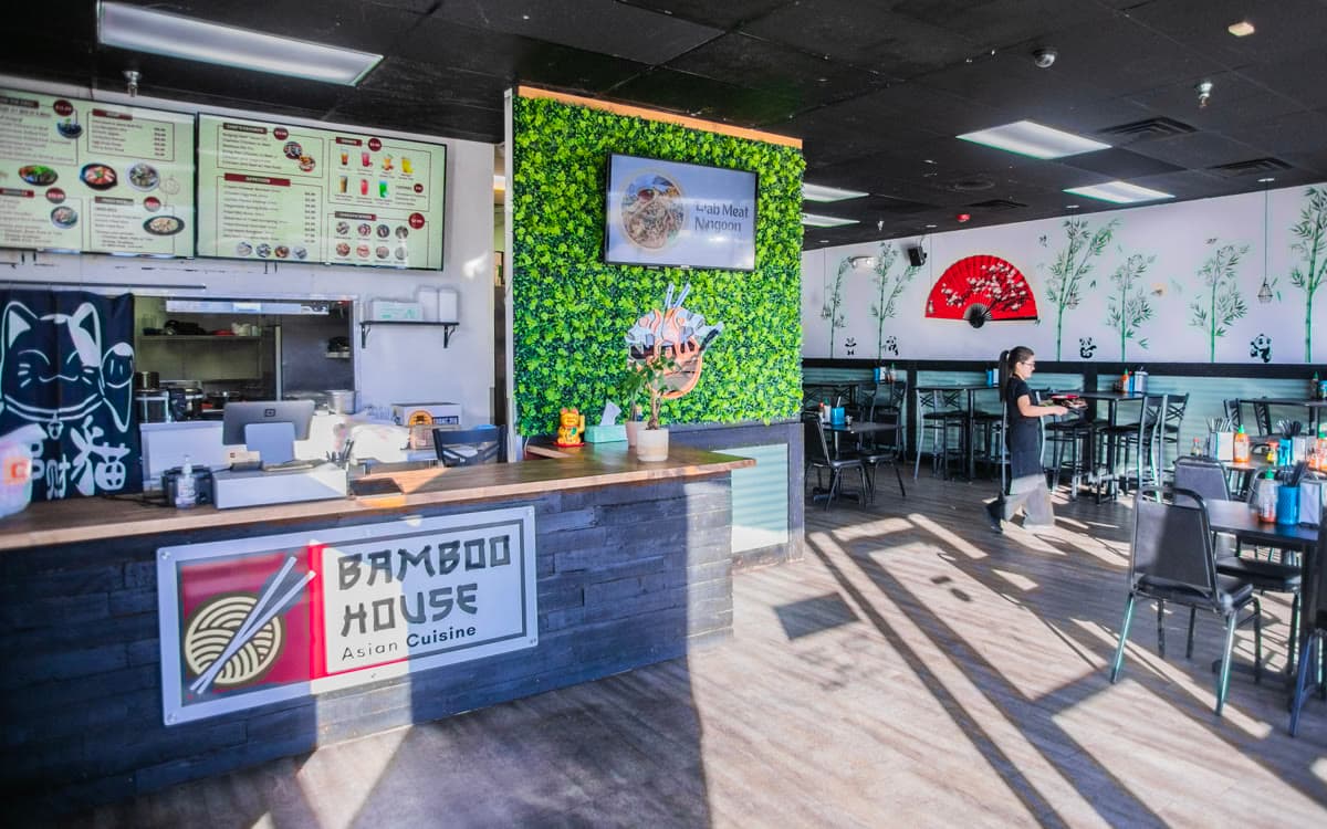 The dining room at Bamboo House Express with black tables and a bamboo wall