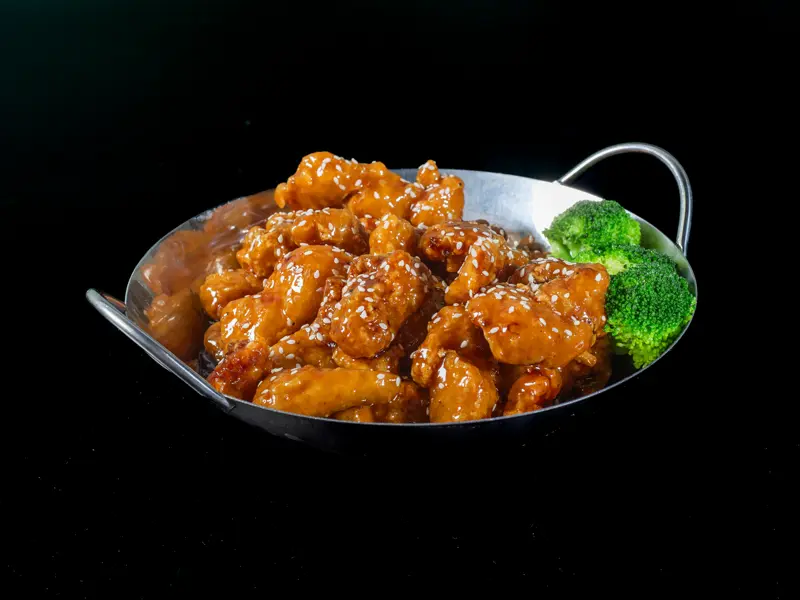 Sesame chicken with broccoli in a steel wok
