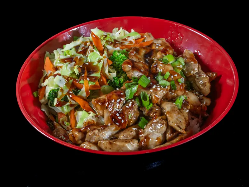 Teriyaki chicken with cabbage slaw on a red plate